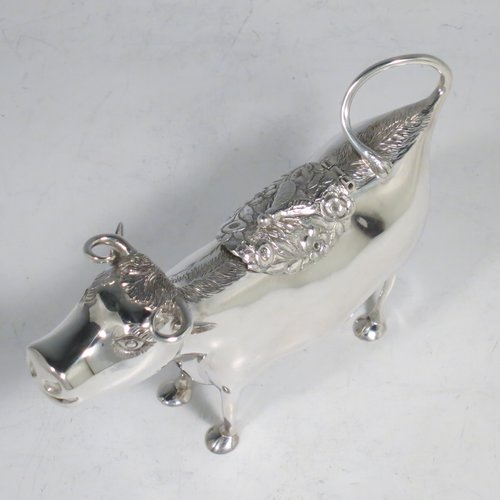 An Antique Victorian Sterling Silver Dutch Cow cream jug, in a George II Cow creamer style, having a hinged lid with hand-chased flowers and an applied model of a bee, with a handle made from from the cows looped tail, and a spout made from the cows mouth, all sitting on four hoof feet. Made in ca. 1880 with Dutch hallmarks. The dimensions of this fine hand-made silver cow creamer are length 14.5 cms (5.75 inches), height 10 cms (4 inches), and it weighs approx. 126g (4 troy ounces).