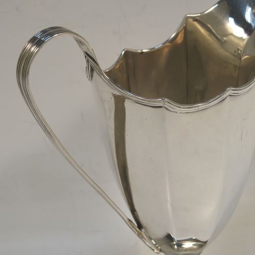 A very handsome Antique Georgian Sterling Silver cream jug, having a plain panelled octagonal body with tapering sides in a Helmet style, a reeded scroll handle and applied top border, and sitting on a pedestal foot with an octagonal shaped base. This beautiful silver cream jug was made by Henry Chawner of London in 1787. The dimensions of this fine hand-made antique silver cream jug are length 13 cms (5 inches), height 14.5 cms (5.75 inches), and it weighs approx. 153g (4.9 troy ounces). Please note that this item is crested.