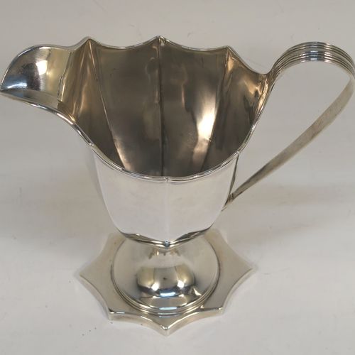 A very handsome Antique Georgian Sterling Silver cream jug, having a plain panelled octagonal body with tapering sides in a Helmet style, a reeded scroll handle and applied top border, and sitting on a pedestal foot with an octagonal shaped base. This beautiful silver cream jug was made by Henry Chawner of London in 1787. The dimensions of this fine hand-made antique silver cream jug are length 13 cms (5 inches), height 14.5 cms (5.75 inches), and it weighs approx. 153g (4.9 troy ounces). Please note that this item is crested.