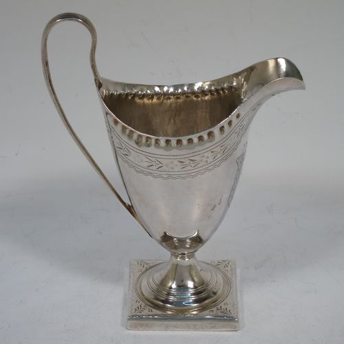 A pretty Antique Georgian Sterling Silver cream jug, having a round body with tapering sides in a Helmet style, with an upper band of floral decoration, a vacant front cartouche, a hand-punched bead border, a scroll handle, and sitting on a pedestal foot with a square base. Made by Peter and Anne Bateman of London in 1792. The dimensions of this fine hand-made antique silver cream jug are length 10 cms (4 inches), height 13 cms (5 inches), and it weighs approx. 84g (2.7 troy ounces).   