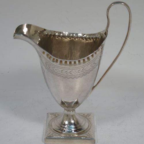 A pretty Antique Georgian Sterling Silver cream jug, having a round body with tapering sides in a Helmet style, with an upper band of floral decoration, a vacant front cartouche, a hand-punched bead border, a scroll handle, and sitting on a pedestal foot with a square base. Made by Peter and Anne Bateman of London in 1792. The dimensions of this fine hand-made antique silver cream jug are length 10 cms (4 inches), height 13 cms (5 inches), and it weighs approx. 84g (2.7 troy ounces).