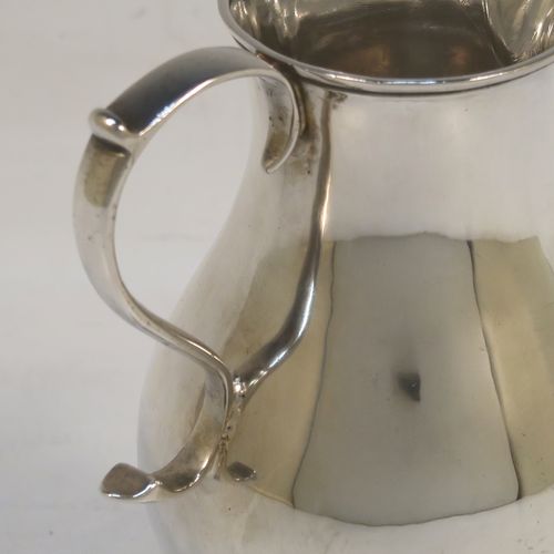 A very handsome Antique Georgian Sterling Silver cream jug, in the sparrow-beak style, having a plain round bellied body, scroll handle, and sitting on a round pedestal foot. This beautiful silver cream jug was made by Henry Brind of London in 1746. The dimensions of this fine hand-made antique silver cream jug are height 10 cms (4 inches), length 8 cms (3 inches), and it weighs approx. 81g (2.6 troy ounces).
