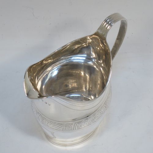 A very elegant Antique Georgian Sterling Silver cream jug, having a round bellied body with hand-chased bands of stipple and floral work, an applied reeded border and reeded scroll handle, and all sitting on a flat base. Made George Burrows of London in 1800. The dimensions of this fine hand-made antique silver cream jug are height 11 cms (4.25 inches), length 11.5 cms (4.5 inches), and it weighs approx. 101g (3.3 troy ounces).