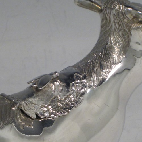 Sterling silver Cow cream jug, in a George II Cow creamer style, having a hinged lid with hand-chased flowers and an applied model of a bee, with a handle made from from the cows looped tail, and a spout made from the cows mouth, all sitting on four hoof feet! Made by Garrards & Co. Ltd., of London in 1978. The dimensions of this fine hand-made silver cow creamer are length 15 cms (6 inches), height 10 cms (4 inches), and it weighs approx. 152g (5 troy ounces).