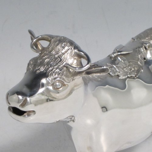 Sterling silver Cow cream jug, in a George II Cow creamer style, having a hinged lid with hand-chased flowers and an applied model of a bee, with a handle made from from the cows looped tail, and a spout made from the cows mouth, all sitting on four hoof feet! Made by Garrards & Co. Ltd., of London in 1978. The dimensions of this fine hand-made silver cow creamer are length 15 cms (6 inches), height 10 cms (4 inches), and it weighs approx. 152g (5 troy ounces).
