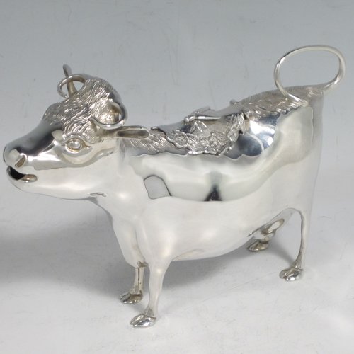 Sterling silver Cow cream jug, in a George II Cow creamer style, having a hinged lid with hand-chased flowers and an applied model of a bee, with a handle made from from the cows looped tail, and a spout made from the cows mouth, all sitting on four hoof feet! Made by Garrards & Co. Ltd., of London in 1978. The dimensions of this fine hand-made silver cow creamer are length 15 cms (6 inches), height 10 cms (4 inches), and it weighs approx. 152g (5 troy ounces).