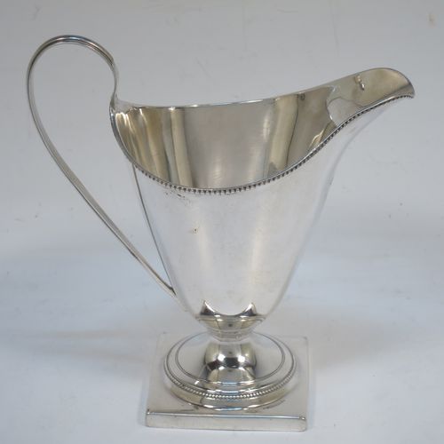 A very elegant Antique Georgian Sterling Silver cream jug, having a round body with tapering sides in a Helmet style, an applied bead-edged border, a reeded scroll handle, and sitting on a pedestal foot with a square base. Made in London in 1790. The dimensions of this fine hand-made antique silver cream jug are length 12 cms (4.75 inches), height 13 cms (5 inches), and it weighs approx. 117g (3.8 troy ounces). Please note that this item is crested.   