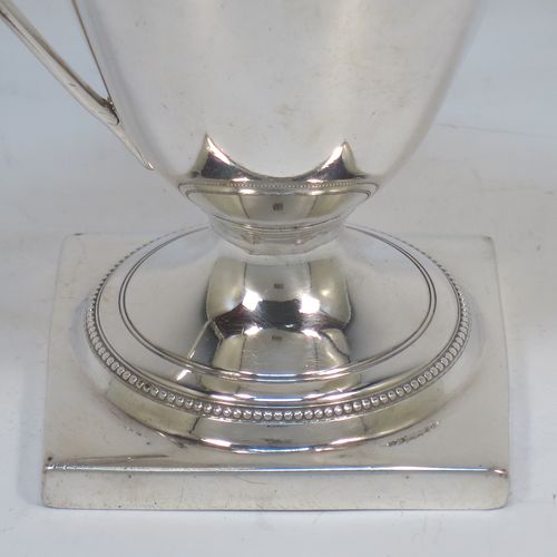 A very elegant Antique Georgian Sterling Silver cream jug, having a round body with tapering sides in a Helmet style, an applied bead-edged border, a reeded scroll handle, and sitting on a pedestal foot with a square base. Made in London in 1790. The dimensions of this fine hand-made antique silver cream jug are length 12 cms (4.75 inches), height 13 cms (5 inches), and it weighs approx. 117g (3.8 troy ounces). Please note that this item is crested.