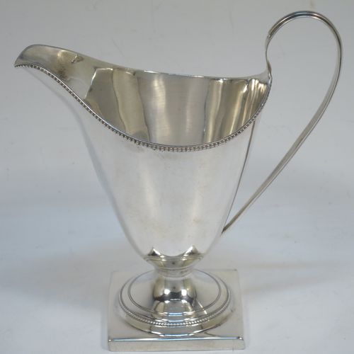 A very elegant Antique Georgian Sterling Silver cream jug, having a round body with tapering sides in a Helmet style, an applied bead-edged border, a reeded scroll handle, and sitting on a pedestal foot with a square base. Made in London in 1790. The dimensions of this fine hand-made antique silver cream jug are length 12 cms (4.75 inches), height 13 cms (5 inches), and it weighs approx. 117g (3.8 troy ounces). Please note that this item is crested.