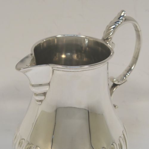 A pretty Antique Victorian Sterling Silver cream jug, in a George I Sparrow-Beak style with a bellied body having hand-chased half-fluted decoration, a plain scroll side-handle, a sparrow-beak spout, and sitting on a collet foot. This beautiful silver cream jug was made by Arthur Sibley of London in 1890. The dimensions of this fine hand-made antique silver cream jug are height 11 cms (4.25 inches), length 9 cms (3.5 inches), and it weighs approx. 121g (3.9 troy ounces).