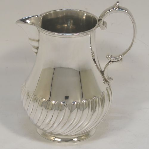 A pretty Antique Victorian Sterling Silver cream jug, in a George I Sparrow-Beak style with a bellied body having hand-chased half-fluted decoration, a plain scroll side-handle, a sparrow-beak spout, and sitting on a collet foot. This beautiful silver cream jug was made by Arthur Sibley of London in 1890. The dimensions of this fine hand-made antique silver cream jug are height 11 cms (4.25 inches), length 9 cms (3.5 inches), and it weighs approx. 121g (3.9 troy ounces).