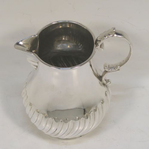 A pretty Antique Victorian Sterling Silver cream jug, in a George I Sparrow-Beak style with a bellied body having hand-chased half-fluted decoration, a plain scroll side-handle, a sparrow-beak spout, and sitting on a collet foot. This beautiful silver cream jug was made by Arthur Sibley of London in 1890. The dimensions of this fine hand-made antique silver cream jug are height 11 cms (4.25 inches), length 9 cms (3.5 inches), and it weighs approx. 121g (3.9 troy ounces).