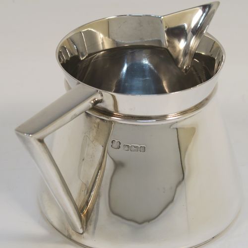An unusual Arts and Crafts style Antique Sterling Silver cream jug, having a plain round body with tapering sides, an angular side-handle, a sparrow-beak spout, and sitting on a flat base. This beautiful silver cream jug was made by Pearce and Sons of Sheffield in 1913. The dimensions of this fine hand-made antique Arts and Crafts silver cream jug are height 7 cms (2.75 inches), length 13.5 cms (5.25 inches), and it weighs approx. 168g (5.4 troy ounces).