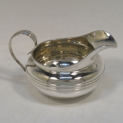 A very elegant Antique Georgian Sterling Silver milk or cream jug, having a plain round bellied body with, applied reeded decoration, a scroll side handle, and sitting on a collet foot. This handsome antique silver cream or milk jug was made by Emes and Barnard of London in 1823. The dimensions of this fine hand-made antique silver jug are height 8.5 cms (3.3 inches), length 14 cms (5.5 inches), and it weighs approx. 221g (7 troy ounces).   