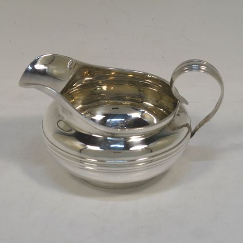 A very elegant Antique Georgian Sterling Silver milk or cream jug, having a plain round bellied body with, applied reeded decoration, a scroll side handle, and sitting on a collet foot. This handsome antique silver cream or milk jug was made by Emes and Barnard of London in 1823. The dimensions of this fine hand-made antique silver jug are height 8.5 cms (3.3 inches), length 14 cms (5.5 inches), and it weighs approx. 221g (7 troy ounces).