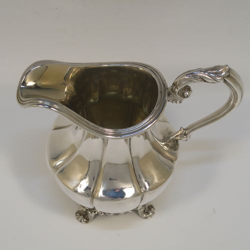 A very pretty and large Antique early Victorian Sterling Silver milk or cream jug, having a round body with hand-chased melon fluting, an applied reeded top border, a scroll handle with anthemion leaf thumb-piece, a gold-gilt interior, and all sitting on four cast foliate feet. This beautiful silver milk jug was made by Hayne and Cater of London in 1837. The dimensions of this fine hand-made antique silver cream jug are height 14 cms (4.5 inches), length 15 cms (6 inches), and it weighs approx. 237g (7.6 troy ounces).