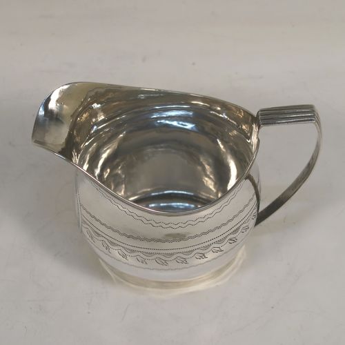 A very pretty Antique Georgian Sterling Silver cream jug, having a round bellied body with hand-engraved bands of stipple and floral work, an applied reeded border and reeded scroll handle, and all sitting on a flat base. This elegant antique silver cream jug was made by Urquart and Hart of London in 1786. The dimensions of this fine hand-made antique silver cream jug are height cms (3.75 inches), length 11 cms (4.3 inches), and it weighs approx. 78g (2.5 troy ounces).