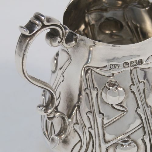 A very pretty Arts and Crafts Antique Edwardian Sterling Silver cream or milk jug having a round bellied body with hand-chased poppy seed head and leaf floral decoration, a cast scroll side-handle, and sitting on three cast trefoil feet. This beautiful Arts and Crafts style silver milk jug was made by Lee and Wigfull (Henry Wigfull) of Sheffield in 1903. The dimensions of this fine hand-made antique silver cream jug are height 9 cms (3.5 inches), length 9 cms (3.5 inches), and it weighs approx. 114g (3.7 troy ounces).