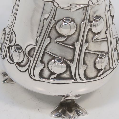 A very pretty Arts and Crafts Antique Edwardian Sterling Silver cream or milk jug having a round bellied body with hand-chased poppy seed head and leaf floral decoration, a cast scroll side-handle, and sitting on three cast trefoil feet. This beautiful Arts and Crafts style silver milk jug was made by Lee and Wigfull (Henry Wigfull) of Sheffield in 1903. The dimensions of this fine hand-made antique silver cream jug are height 9 cms (3.5 inches), length 9 cms (3.5 inches), and it weighs approx. 114g (3.7 troy ounces).