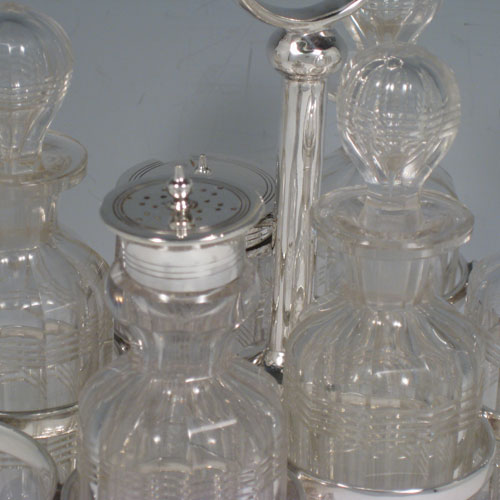 Antique Victorian sterling silver cruet set, having a plain stand with ring handle and frame for six hand-cut crystal cruet bottles with original stoppers and silver mounts, all sitting on a base with four cushion feet. Made by William Hutton and Sons of Sheffield in 1901. Height 22 cms (8.75 inches), length 16.5 cms (6.5 inches), width 13 cms (5 inches). Total weight approx. 650g (21 troy ounces).