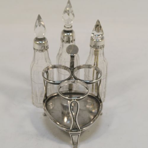 A small but very pretty Antique Victorian Sterling Silver and crystal bottle cruet set, having a plain frame with applied reeded borders, a matching side-handle with thumb-piece, three original crystal bottles with stoppers and silver collars, two for oil and vinegar and the third for mustard or chili sauce with its original gold-gilt spoon, all sitting on a base with three flange feet. This beautiful cruet set was made by Francis Boone Thomas of London in 1873. The dimensions of this fine hand-made antique silver cruet set are height 13.5 cms (5.3 inches), length 7.5 cms (3 inches), and width 6 cms (2.3 inches).