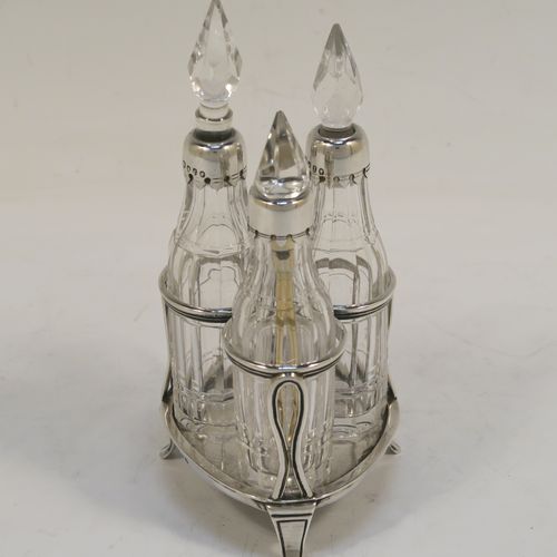 A small but very pretty Antique Victorian Sterling Silver and crystal bottle cruet set, having a plain frame with applied reeded borders, a matching side-handle with thumb-piece, three original crystal bottles with stoppers and silver collars, two for oil and vinegar and the third for mustard or chili sauce with its original gold-gilt spoon, all sitting on a base with three flange feet. This beautiful cruet set was made by Francis Boone Thomas of London in 1873. The dimensions of this fine hand-made antique silver cruet set are height 13.5 cms (5.3 inches), length 7.5 cms (3 inches), and width 6 cms (2.3 inches).
