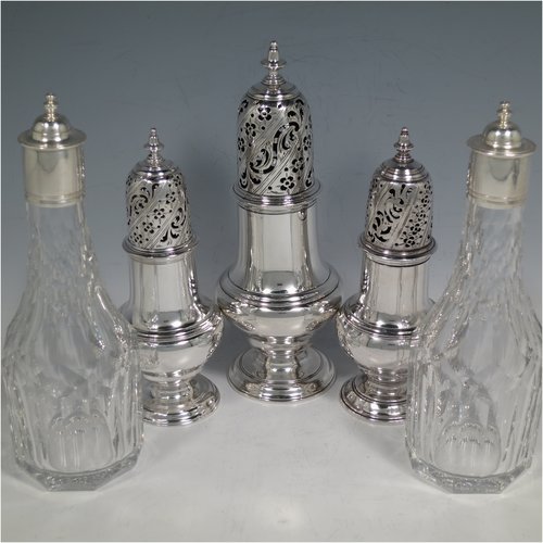 An Antique Georgian Sterling Silver and hand-cut crystal five-bottle Warwick style cruet set, having a stand with ring & scroll work holders, a cast loop handle with shell, a cast applied shell-style cartouche, and sitting on four cast shell feet. With two smaller baluster style pepper pots, a larger baluster sugar caster, and two hand-cut crystal oil & vinegar bottles with silver tops. Made by Samuel Woods of London in 1752-1754. The dimensions of this fine hand-made silver cruet set are width of stand 20 cms (8 inches), height of stand 23 cms (9 inches), and weight of silver approx. 1,500g (48 troy ounces). Please note that the silver tops on the crystal bottles are unmarked, and the stand is crested.