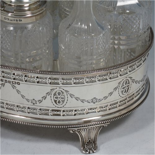 An Antique Victorian Sterling Silver large table cruet set, having a Neoclassical style oval stand with applied bead borders and hand-pierced and engraved decoration, with ring handle and a frame for seven hand-cut crystal cruet bottles with original stoppers and silver mounts, all sitting on a base with four flange feet. Made by James Dixon & Sons of Sheffield in 1872. The dimensions of this fine antique silver cruet set are height 26 cms (10.25 inches), length 20 cms (8 inches), width 16 cms (6.25 inches),and with a total weight of approx. 900g (29 troy ounces).