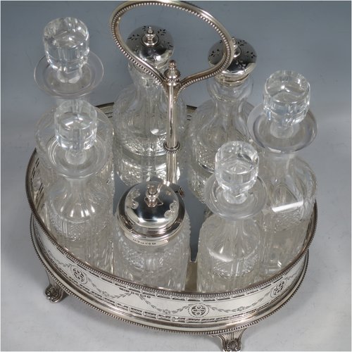 An Antique Victorian Sterling Silver large table cruet set, having a Neoclassical style oval stand with applied bead borders and hand-pierced and engraved decoration, with ring handle and a frame for seven hand-cut crystal cruet bottles with original stoppers and silver mounts, all sitting on a base with four flange feet. Made by James Dixon & Sons of Sheffield in 1872. The dimensions of this fine antique silver cruet set are height 26 cms (10.25 inches), length 20 cms (8 inches), width 16 cms (6.25 inches),and with a total weight of approx. 900g (29 troy ounces).