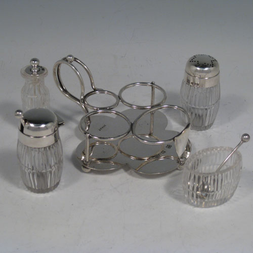 Antique Victorian sterling silver and hand-cut crystal small cruet set with open salt and spoon, mustard pot with lid and spoon, pepper pot with removable lid, and a chilli sauce pot with attached spoon. All sitting inside a wire-work frame with scroll handle and plain base sitting on four ball feet. All spoons are original. Made by Heath and Middleton of London in 1896. Length 12 cms (4.75 inches), width 9.5 cms (3.75 inches), height 7 cms (2.75 inches).