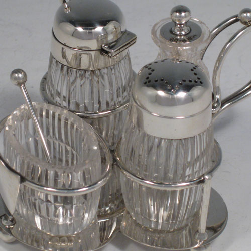 Antique Victorian sterling silver and hand-cut crystal small cruet set with open salt and spoon, mustard pot with lid and spoon, pepper pot with removable lid, and a chilli sauce pot with attached spoon. All sitting inside a wire-work frame with scroll handle and plain base sitting on four ball feet. All spoons are original. Made by Heath and Middleton of London in 1896. Length 12 cms (4.75 inches), width 9.5 cms (3.75 inches), height 7 cms (2.75 inches).