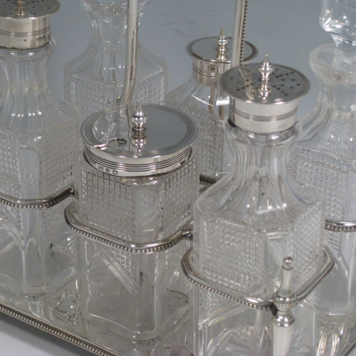 Antique Victorian sterling silver and hand-cut crystal cruet set, having six bottles with reeded mounts, sitting in a rectangular frame with bead edges, on four cushion feet. The frame was made by Walker and Hall of Sheffield in 1900, and the bottles by Bewlay & Co. of Birmingham between 1897 and 1900. Height of frame 22 cms (8.75 inches), length 18 cms (7 inches), width 13 cms (5 inches). Weight of stand approx. 729g (23.5 troy ounces).