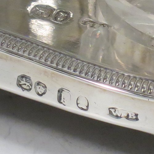 An Antique Georgian Sterling Silver large table cruet set, having a Regency style rectangular stand with an applied gadroon border, with ring handle and a frame for six hand-cut crystal cruet bottles with original stoppers and silver mounts, all sitting on a base with four cast lions paw feet. Made by William Bateman I of London in 1825. The dimensions of this fine antique silver cruet set are height 20 cms (8 inches), length 15 cms (6 inches), and width 13 cms (5 inches). Please note that the base has a wooden insert underneath.