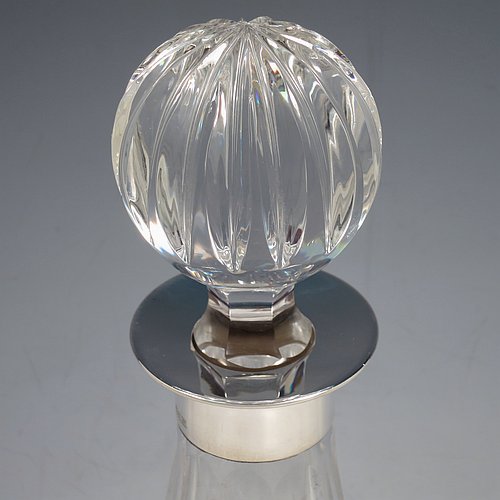 A Sterling Silver and hand-cut crystal decanter, having a round bellied body with tapering sides, hand-cut hobnail and diamond decoration, a silver collar with lip, an original fluted stopper, and sitting on a flat star-cut base. Made by Garrard & Co., of Birmingham in 1971. The dimensions of this fine silver and crystal decanter are height 28 cms (11 inches), and diameter at base 17 cms (6.75 inches).