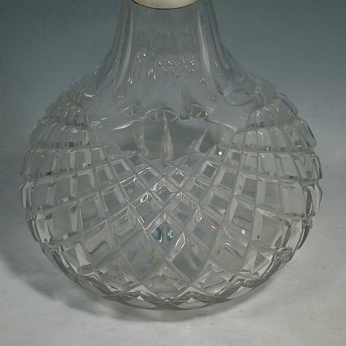 A Sterling Silver and hand-cut crystal decanter, having a round bellied body with tapering sides, hand-cut hobnail and diamond decoration, a silver collar with lip, an original fluted stopper, and sitting on a flat star-cut base. Made by Garrard & Co., of Birmingham in 1971. The dimensions of this fine silver and crystal decanter are height 28 cms (11 inches), and diameter at base 17 cms (6.75 inches).