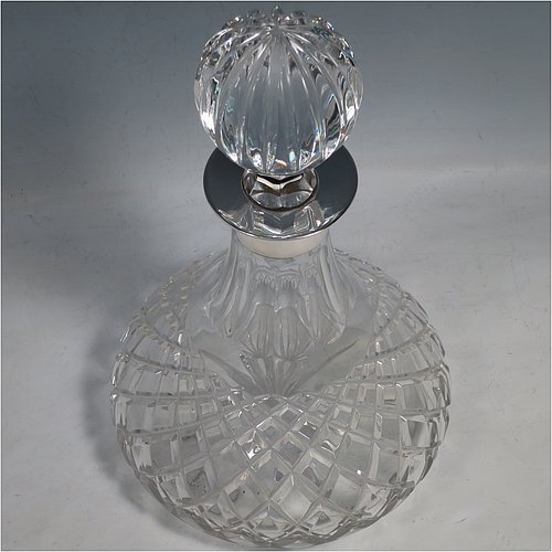 A Sterling Silver and hand-cut crystal decanter, having a round bellied body with tapering sides, hand-cut hobnail and diamond decoration, a silver collar with lip, an original fluted stopper, and sitting on a flat star-cut base. Made by Garrard & Co., of Birmingham in 1971. The dimensions of this fine silver and crystal decanter are height 28 cms (11 inches), and diameter at base 17 cms (6.75 inches).