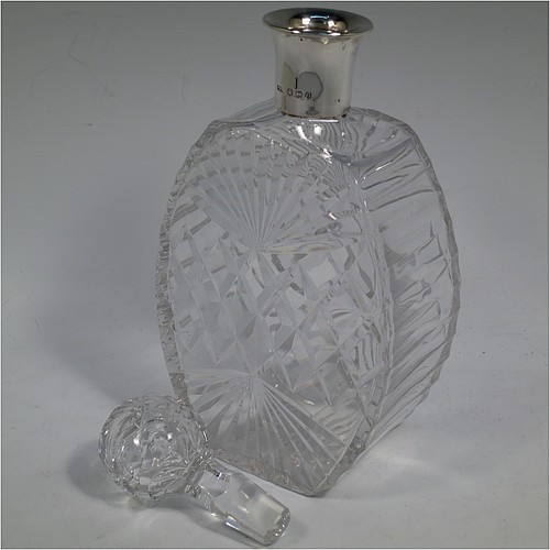 A very unusually designed Sterling Silver and hand-cut crystal decanter, having a main oval body at front and back with hobnail and star-burst cut, and with tapering sides having stepped decoration, a plain silver collar, an original hand-cut stopper, and sitting on a flat base with a matching star-cut. Made by Mappin and Webb of Sheffield in 1956. The dimensions of this fine hand-made silver and crystal decanter are height 25.5 cms (10 inches), width 12 cms (4.75 inches), and depth at base 7 cms (2.75 inches).