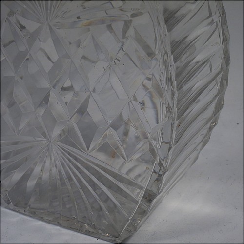 A very unusually designed Sterling Silver and hand-cut crystal decanter, having a main oval body at front and back with hobnail and star-burst cut, and with tapering sides having stepped decoration, a plain silver collar, an original hand-cut stopper, and sitting on a flat base with a matching star-cut. Made by Mappin and Webb of Sheffield in 1956. The dimensions of this fine hand-made silver and crystal decanter are height 25.5 cms (10 inches), width 12 cms (4.75 inches), and depth at base 7 cms (2.75 inches).