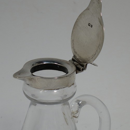 A Sterling Silver pair of whisky toddies or noggins, having round based hand-cut crystal bodies with tapering sides and loop handles, mounted with silver collars and hinged flat lids with thumb-pieces, all sitting on flat star-cut bases. Made by Goldsmiths and Silversmiths of London in 1932. The dimensions of this fine hand-made pair of silver and crystal noggins or toddies are height 11 cms (4.25 inches), and diameter at bases 6.5 cms (2.5 inches).   