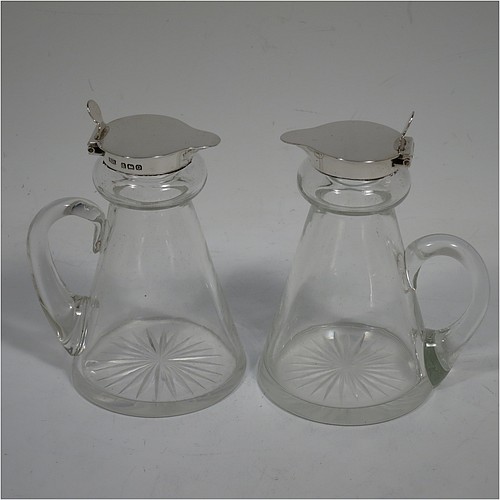 A very handsome pair of Antique Sterling Silver and crystal whisky toddies or noggins, having round hand-cut crystal bodies with tapering sides and loop handles, mounted with silver collars and hinged flat lids with thumb-pieces, all sitting on flat star-cut bases. Made by Hukin and Heath of Birmingham in 1913. The dimensions of this fine hand-made pair of antique silver and crystal noggins or toddies are height 10 cms (4 inches), and diameter at bases 6.5 cms (2.5 inches).    