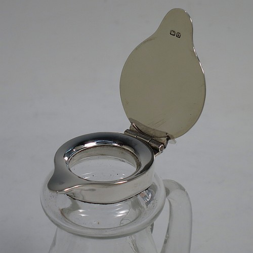 A very handsome pair of Antique Sterling Silver and crystal whisky toddies or noggins, having round hand-cut crystal bodies with tapering sides and loop handles, mounted with silver collars and hinged flat lids with thumb-pieces, all sitting on flat star-cut bases. Made by Hukin and Heath of Birmingham in 1913. The dimensions of this fine hand-made pair of antique silver and crystal noggins or toddies are height 10 cms (4 inches), and diameter at bases 6.5 cms (2.5 inches).