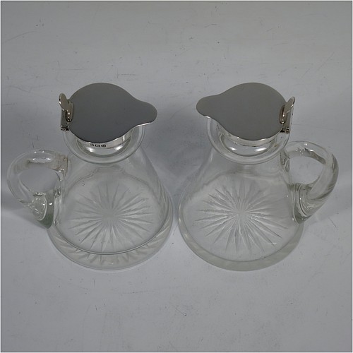 A very handsome pair of Antique Sterling Silver and crystal whisky toddies or noggins, having round hand-cut crystal bodies with tapering sides and loop handles, mounted with silver collars and hinged flat lids with thumb-pieces, all sitting on flat star-cut bases. Made by Hukin and Heath of Birmingham in 1913. The dimensions of this fine hand-made pair of antique silver and crystal noggins or toddies are height 10 cms (4 inches), and diameter at bases 6.5 cms (2.5 inches).