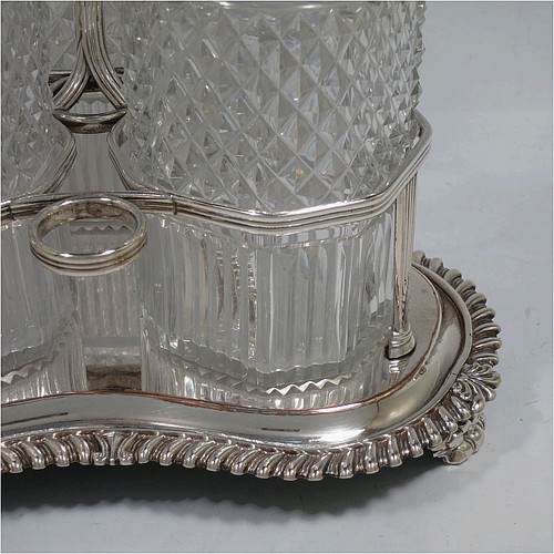 A very handsome Antique Georgian Old Sheffield plated decanter stand, having three hand-cut crystal decanters with original stoppers, sitting inside a carrying frame with a cast anthemion leaf loop handle attached to a hand-chased reeded gallery, which in-turn is attached to a base with shell and gadroon border, and all sitting on three cast scroll feet. Made by Matthew Boulton of Birmingham in ca. 1810. The dimensions of this fine hand-made Old Sheffield plated decanter stand are height 28 cms (11 inches), and width at base 25.5 cms (10 inches).