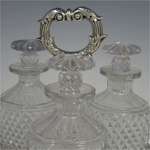 A very handsome Antique Georgian Old Sheffield plated decanter stand, having three hand-cut crystal decanters with original stoppers, sitting inside a carrying frame with a cast anthemion leaf loop handle attached to a hand-chased reeded gallery, which in-turn is attached to a base with shell and gadroon border, and all sitting on three cast scroll feet. Made by Matthew Boulton of Birmingham in ca. 1810. The dimensions of this fine hand-made Old Sheffield plated decanter stand are height 28 cms (11 inches), and width at base 25.5 cms (10 inches).