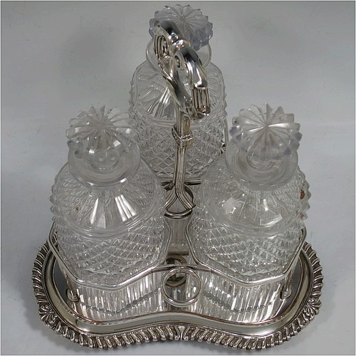 A very handsome Antique Georgian Old Sheffield plated decanter stand, having three hand-cut crystal decanters with original stoppers, sitting inside a carrying frame with a cast anthemion leaf loop handle attached to a hand-chased reeded gallery, which in-turn is attached to a base with shell and gadroon border, and all sitting on three cast scroll feet. Made by Matthew Boulton of Birmingham in ca. 1810. The dimensions of this fine hand-made Old Sheffield plated decanter stand are height 28 cms (11 inches), and width at base 25.5 cms (10 inches).