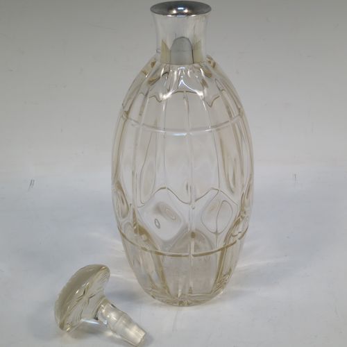 A very unusually designed Sterling Silver and hand-cut crystal decanter, having an oval body , and with hand-cut reeded decoration together with internal lobed work, a plain silver collar, an original hand-cut stopper, and sitting on a flat base with a star-cut. Made by John Grinsell of Birmingham in 1910. The dimensions of this fine hand-made silver and crystal decanter are height 25.5 cms (10 inches), and diameter 10 cms (4 inches).