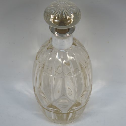 A very unusually designed Sterling Silver and hand-cut crystal decanter, having an oval body , and with hand-cut reeded decoration together with internal lobed work, a plain silver collar, an original hand-cut stopper, and sitting on a flat base with a star-cut. Made by John Grinsell of Birmingham in 1910. The dimensions of this fine hand-made silver and crystal decanter are height 25.5 cms (10 inches), and diameter 10 cms (4 inches).