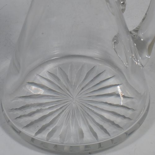 A very handsome pair of Sterling Silver and crystal whisky toddies or noggins, having round based hand-cut crystal bodies with tapering sides and loop handles, mounted with silver collars and hinged flat lids with thumb-pieces, all sitting on flat star-cut bases. Made by Hukin and Heath of Birmingham in 1923. The dimensions of this fine hand-made pair of silver and crystal noggins or toddies are height 11 cms (4.25 inches), and diameter at bases 6.5 cms (2.5 inches).