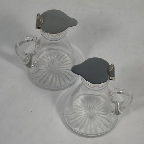 A very handsome pair of Sterling Silver and crystal whisky toddies or noggins, having round based hand-cut crystal bodies with tapering sides and loop handles, mounted with silver collars and hinged flat lids with thumb-pieces, all sitting on flat star-cut bases. Made by Hukin and Heath of Birmingham in 1923. The dimensions of this fine hand-made pair of silver and crystal noggins or toddies are height 11 cms (4.25 inches), and diameter at bases 6.5 cms (2.5 inches).