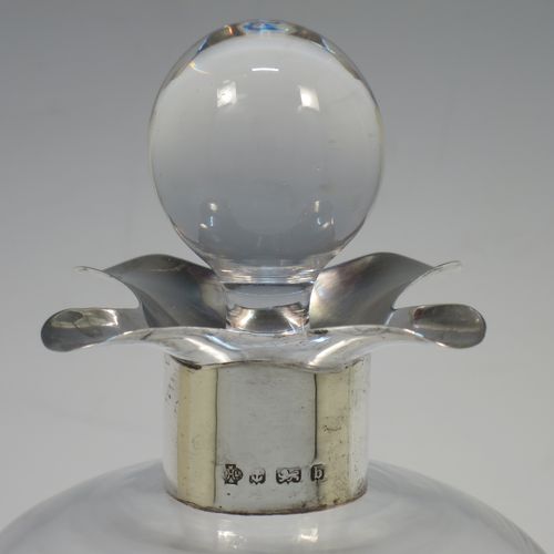 A handsome Antique Victorian Sterling Silver and cut-crystal glug-glug decanter, having a plain and clear body with pinched and fluted central waists, a plain round neck with four pouring spouts, and original hand-cut stopper. Made by William Hutton and Sons of Birmingham in 1901. The dimensions of this fine hand-made antique silver and crystal glug glug decanter are height 27.5 cms (10.75 inches), and width at base 13 cms (5 inches).